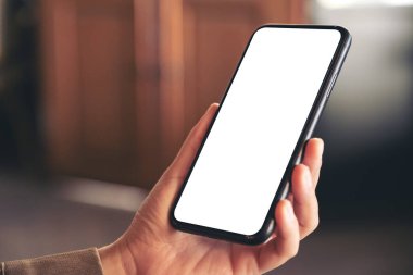 Boş beyaz masaüstü ekran ile siyah cep telefonu tutan bir elin görüntüsü