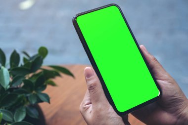 Boş beyaz masaüstü ekran ile siyah cep telefonu tutan ellerin görüntüsü