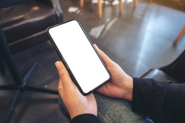 Boş beyaz masaüstü ekran ile siyah cep telefonu tutan ellerin görüntüsü