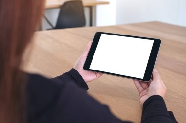 Ofiste otururken elinde tuttuğu ve siyah tabletlere bakan beyaz ekranlı bir kadının görüntüsü.
