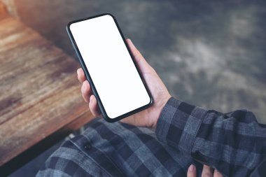 Antika kafede boş beyaz ekran ile siyah cep telefonu tutan ellerin görüntüsü