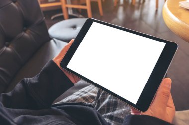 Kafede otururken elinde siyah tablet olan beyaz ekranlı bir kadının görüntüsü.