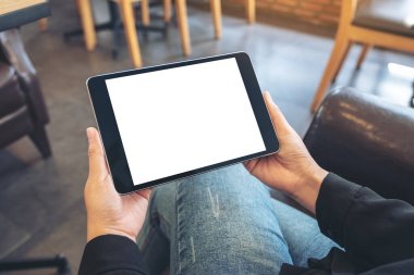 Kafede otururken elinde siyah tablet olan beyaz ekranlı bir kadının görüntüsü.