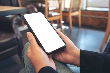 Boş beyaz masaüstü ekran ile siyah cep telefonu tutan ellerin görüntüsü