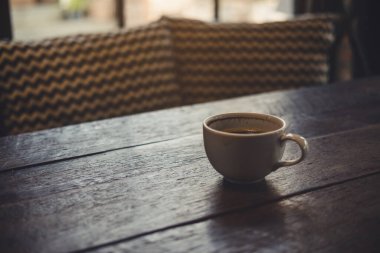 Kafedeki eski ahşap masada sıcak kahve fincanının yakın plan görüntüsü.