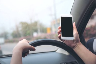 Bir el ele tutuşmanın ve yolda araba sürerken boş siyah masaüstü ekran ile beyaz cep telefonu kullanmanın görüntüsü