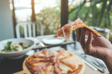Lokantada yemek için Parma jambonlu pizza alan bir elin yakın çekimi.
