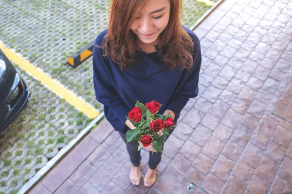 バレンタインデーに幸せを感じる緑の庭に赤いバラの花を持つ美しいアジアの女性 — ストック写真