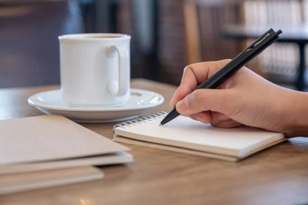 カフェのテーブルの上にコーヒーカップが置かれた空白のノートに手書きのイメージを閉じる — ストック写真