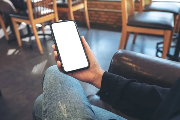 Boş beyaz masaüstü ekran ile siyah cep telefonu tutan bir elin görüntüsü