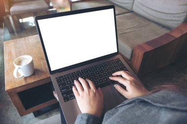 İş kadınının laptopta boş beyaz masaüstü ekran ve kafedeki ahşap masada kahve fincanı kullanarak ve yazarak görüntüsü.