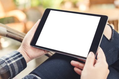 Kafe 'de arka planı bulanık, beyaz ekranlı, elinde siyah tablet olan bir kadının görüntüsü