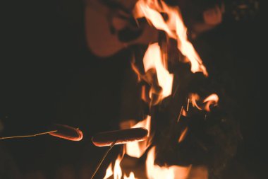  İnsanlar gecenin karanlığında sosis pişirip, kamp ateşiyle gitar çalıyordu. 