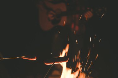  İnsanlar gecenin karanlığında sosis pişirip, kamp ateşiyle gitar çalıyordu. 
