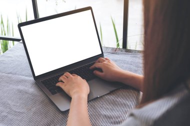 Kafedeki masada boş beyaz masaüstü ekran kullanan ve laptopa dokunan bir kadının görüntüsü
