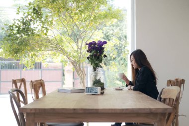 Güzel bir Asyalı kadın kafede kendini rahat hissedip kahve içiyor.