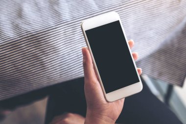 Boş siyah masaüstü ekranlı beyaz cep telefonu tutan ellerin görüntüsü 