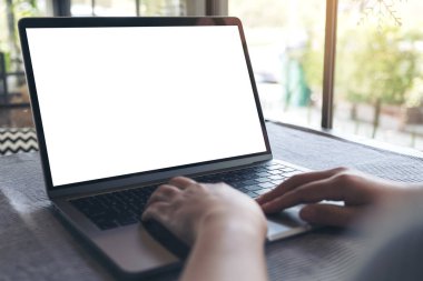 Kafedeki masada boş beyaz masaüstü ekran kullanan ve laptopa dokunan bir elin görüntüsü