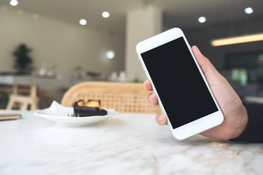 Kafedeki boş siyah masaüstü ekran ile el ele tutuşan ve beyaz cep telefonunu gösteren bir resmin maketi