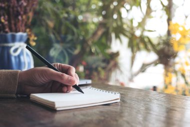 Ahşap masanın üzerine boş bir deftere el yazısının yakın plan resmi. 