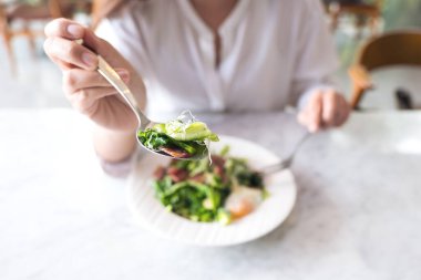 Restoranda yemek yemeden önce kaşıkla salata kepçeleyen bir kadın.