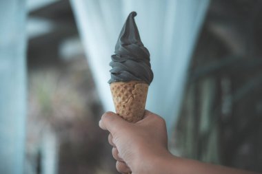 Kömür tutan bir el, arka planı bulanık dondurma külahı.