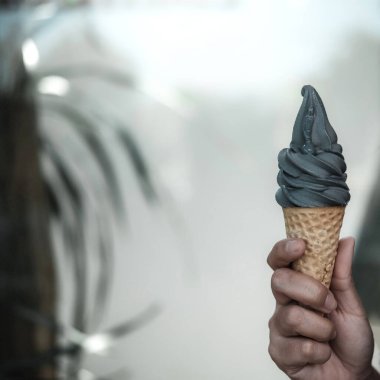 Kömür tutan bir el, arka planı bulanık dondurma külahı.