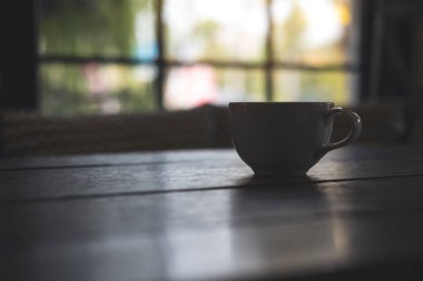 Kafedeki eski ahşap masada sıcak kahve fincanının yakın plan görüntüsü.