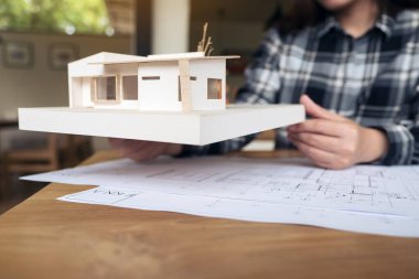 Mimari model üzerinde çalışan bir mimar ve masa üzerine kağıt çizen bir dükkan.