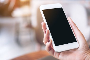 Boş siyah masaüstü ekranı ve bulanık arkaplanı olan beyaz cep telefonunu tutan bir elin görüntüsü