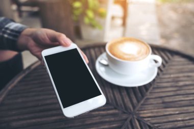 Bir el ele tutuşmanın ve boş siyah masaüstü ekranlı beyaz cep telefonunu kafedeki birine vermenin görüntüsü.