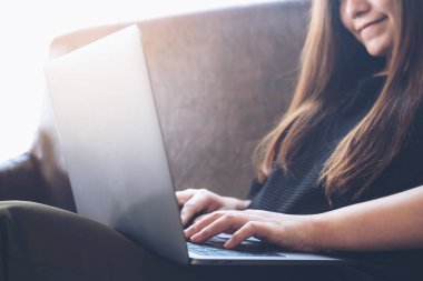 Kanepede otururken dizüstü bilgisayarda çalışan ve daktilo kullanan Asyalı bir kadının yakın plan görüntüsü