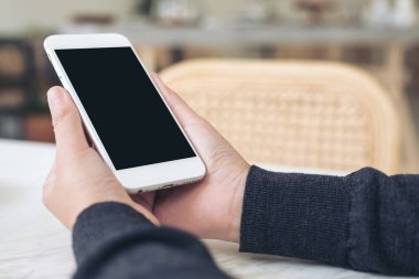 Modern cafe 'de boş siyah masaüstü ekranlı beyaz cep telefonu tutan ellerin görüntüsü