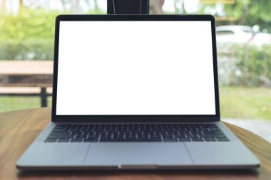 Kafedeki ahşap masada boş beyaz masaüstü ekranı olan dizüstü bilgisayarın görüntüsü 