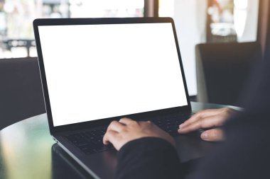 Kafe 'deki boş beyaz ekranla iş kadınının laptopta yazı yazıp kullandığı bir resim.