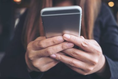 Elinde tutan, kullanan ve akıllı telefona bakan bir kadının yakın plan görüntüsü. 