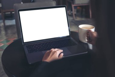 Kafede kahve içerken laptopta beyaz ekran kullanan ve daktilo yazan bir iş kadını görüntüsü.