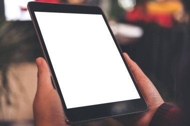 Kafedeki boş beyaz masaüstü ekranlı siyah tableti tutan ve bacak bacak üstüne atmış bir kadının üst görünüm görüntüsü