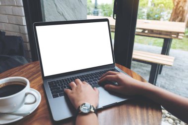 Kafedeki tahta masada boş beyaz masaüstü ekran kullanan ve yazan bir kadının görüntüsü.