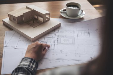 Mimari bir model üzerinde çalışan bir mimar. Masaya kağıt ve kahve fincanı çiziyor.