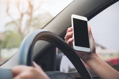 Bir el ele tutuşmanın ve yolda araba sürerken boş siyah masaüstü ekran ile beyaz cep telefonu kullanmanın görüntüsü