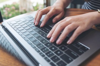Bir iş kadınının ellerinin laptop klavyesinde çalışıp daktilo yazışının en üst görünümü 