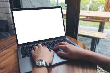 Kafedeki tahta masada boş beyaz masaüstü ekran kullanan ve yazan bir kadının görüntüsü.