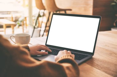Laptop bilgisayarında beyaz ekran ve ahşap masada kahve fincanı kullanan ve daktilo kullanan bir kadının görüntüsü.