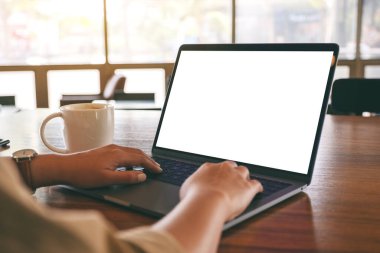Laptop 'ta beyaz ekran ve tahta masada kahve fincanı kullanan ve daktilo kullanan bir kadının görüntüsü.
