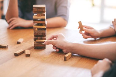 Arkadaşlar birlikte oturup Tumble kulesi tahta blok oyunu oynuyorlar. 