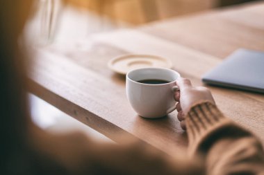 Yakından bakınca, elinde bir fincan sıcak kahve tutan bir kadın görülüyor.