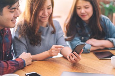 Üç genç Asyalı aynı cep telefonunu kullanıyor ve ona bakıyor.