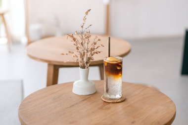 Minimum kafedeki ahşap masada duran bir bardak buzlu hindistan cevizi kahvesinin yakın plan görüntüsü.