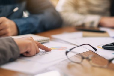 İş adamı, bir toplantıda iş konuşurken evrak işlerine parmak basıyor.